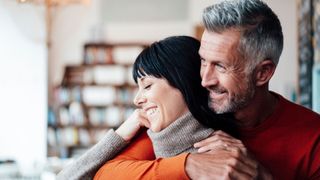 Man with arms round woman at home