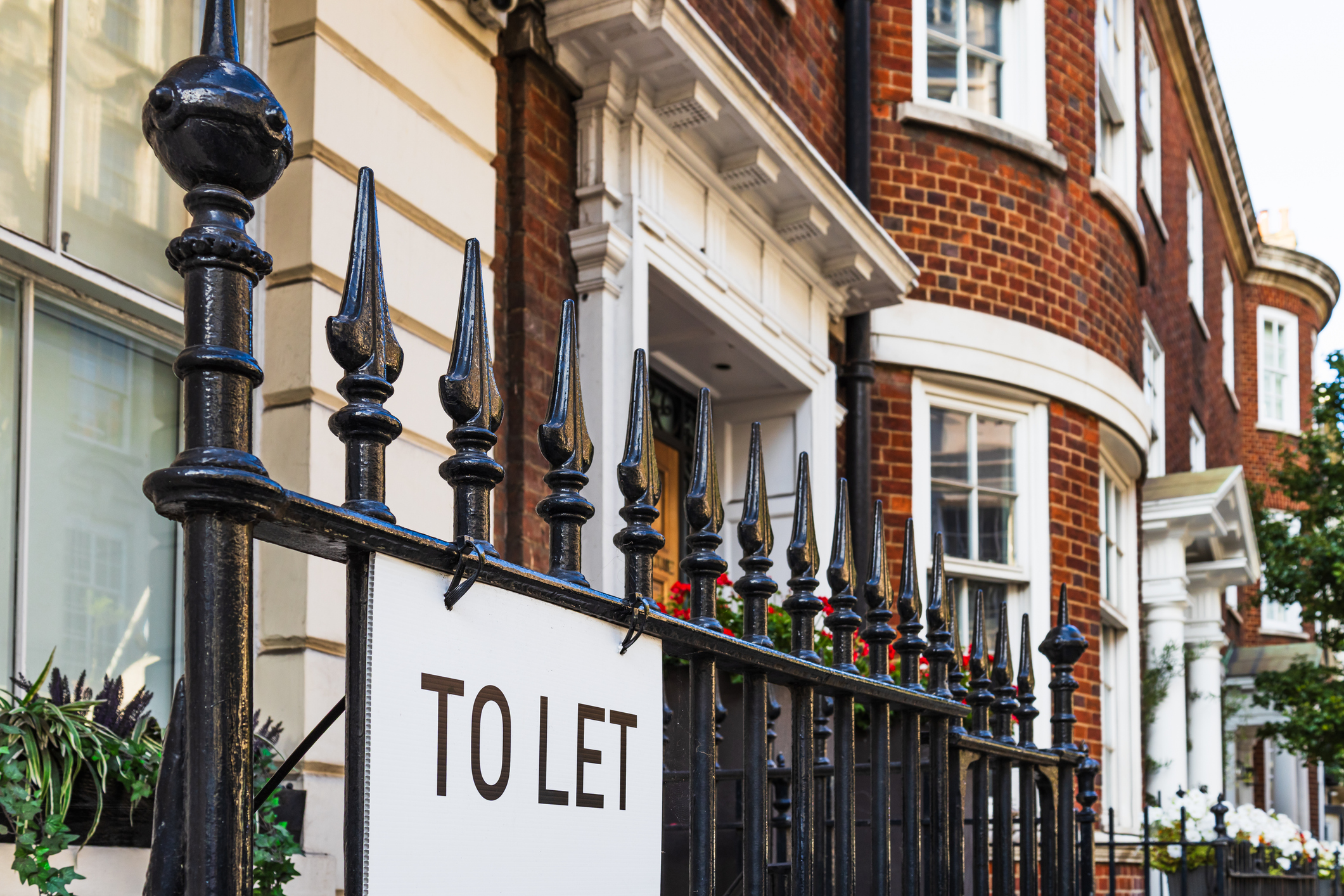 Elegant - To Let - sign on a black iron fence in front of charming London brick townhouses