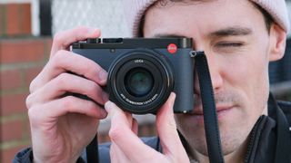 A Leica Q3 43 camera held up to a persons face