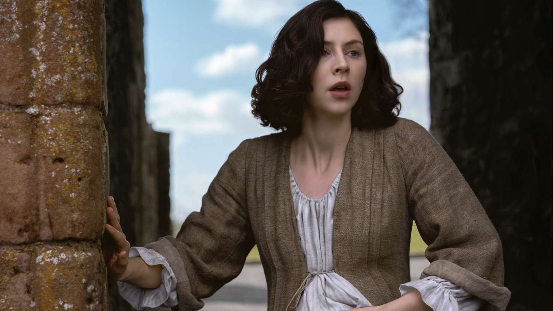 Julia clutches her baby bump while holding onto a wall