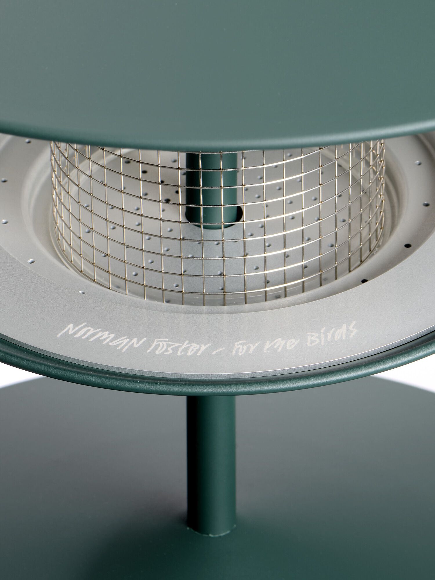A teal-shaded bird house cast from iron and chrome detailing in a concentric, futuristic shape.