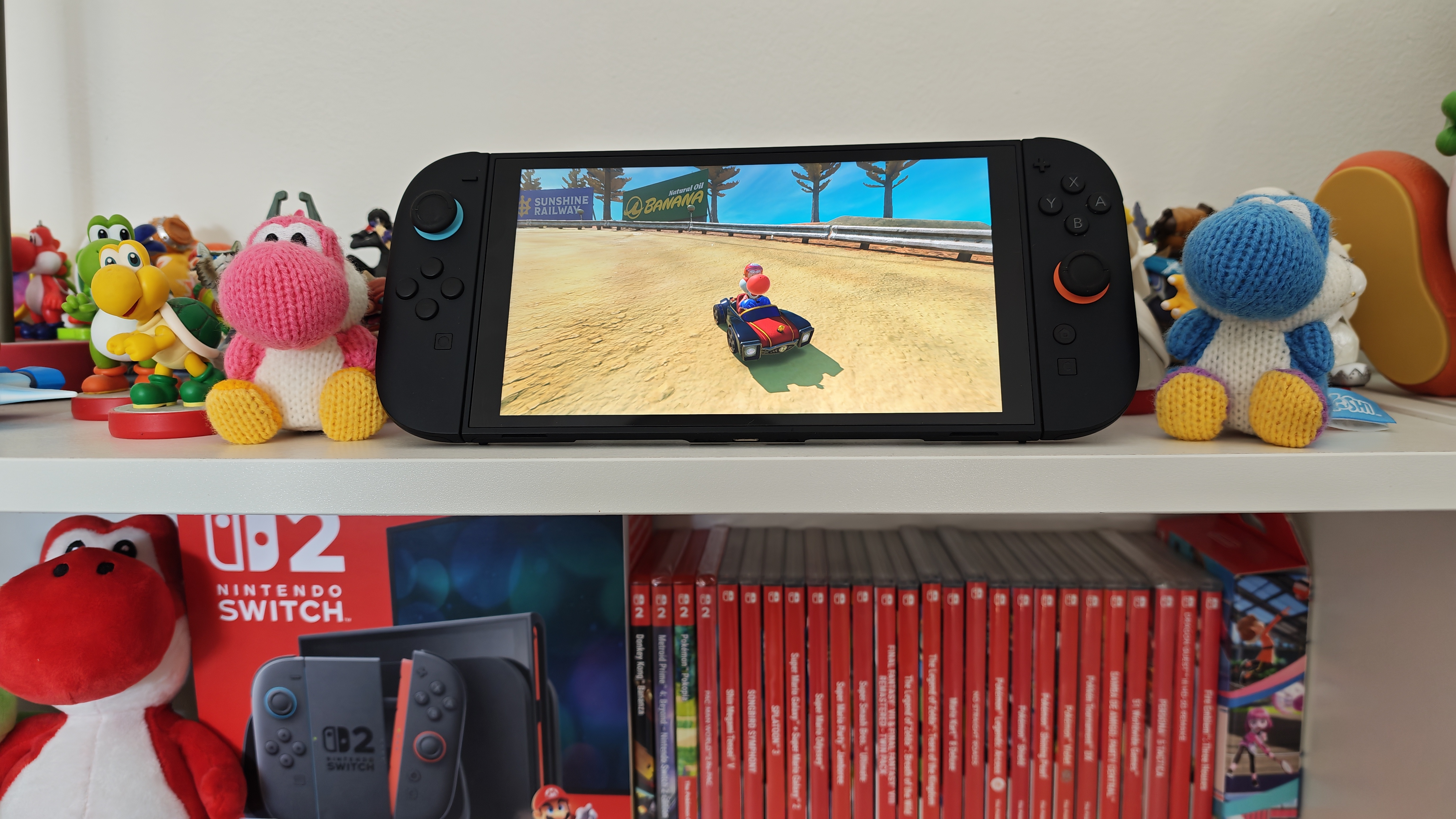 Mario Kart World being played on Switch 2, on shelf with various amiibo
