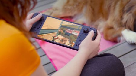 Player using Steam Deck next to dog