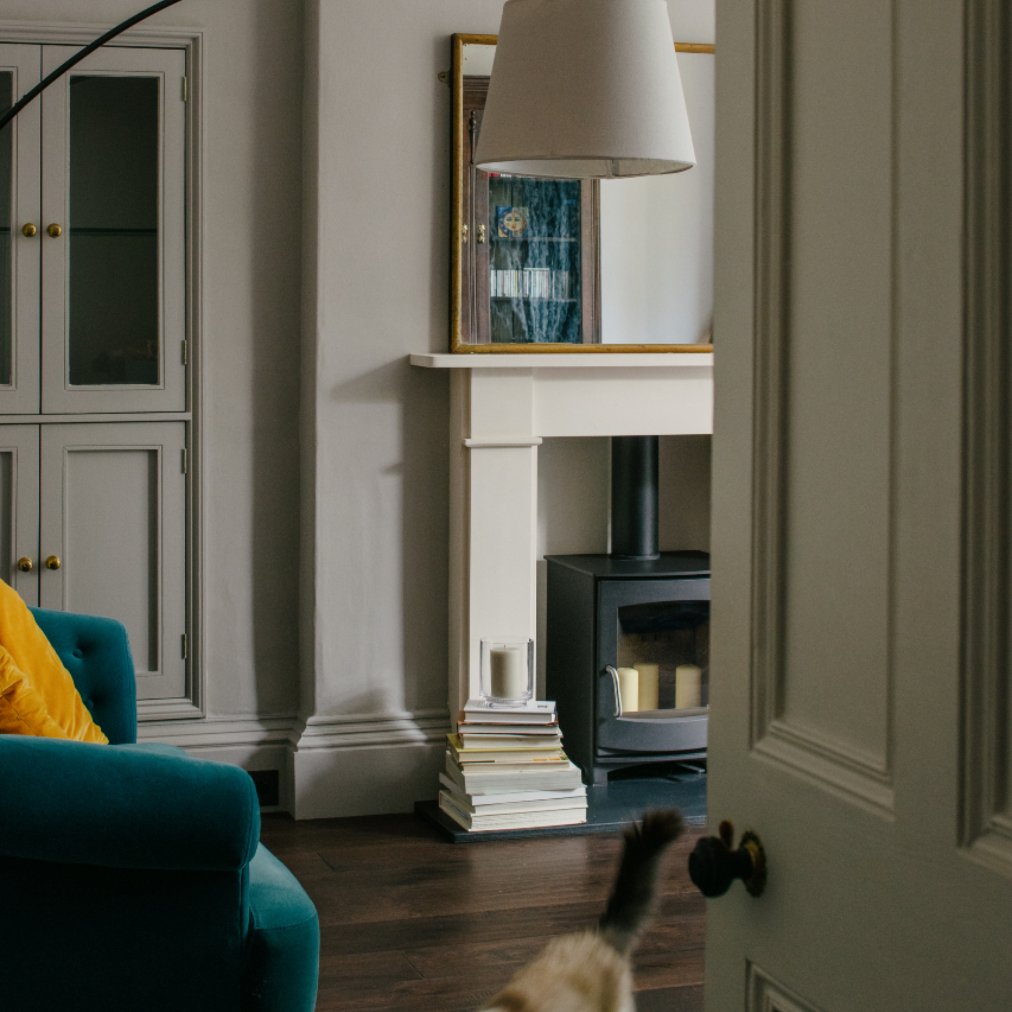 living room with stone coloured walls, built in storage, teal armchair, wooden floor