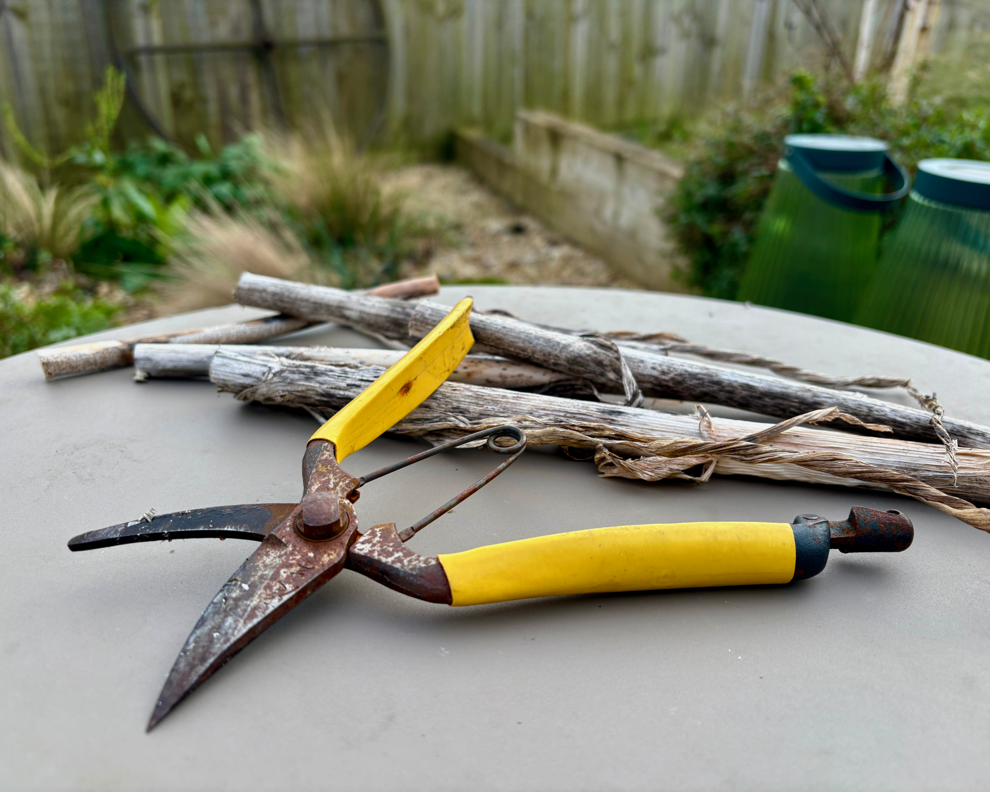 japanese hand pruners with yellow handles on patio table in garden