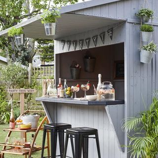 garden area with wooden shed and drinks and black tables