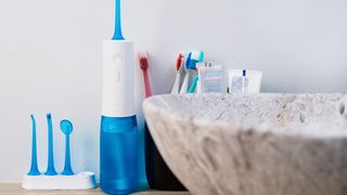 water flosser oral irrigator and heads placed next to the sink in a bathroom