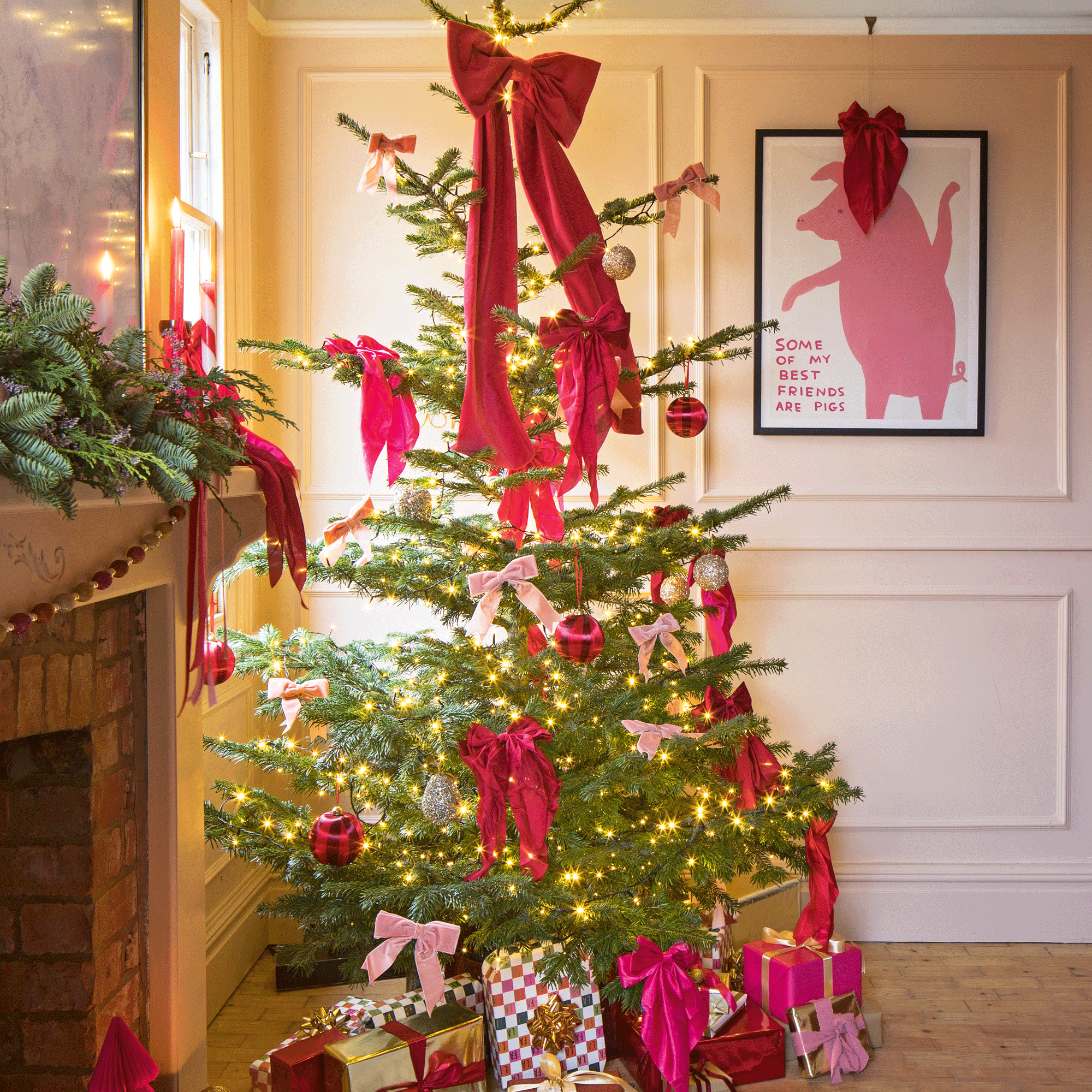 a living room with a Christmas tree covered in large pink/red bows, a mantelpiece with festive greenery, bold typography artwork 