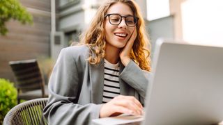 woman in glasses working on laptop outside