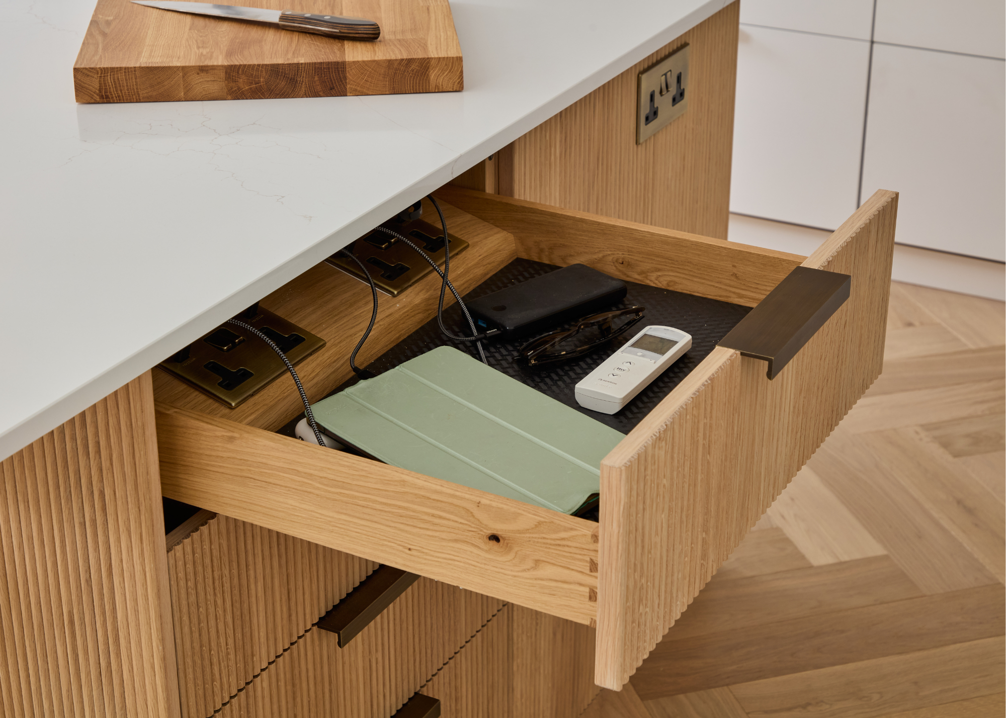 An open drawer with hidden sockets inside and things on charge