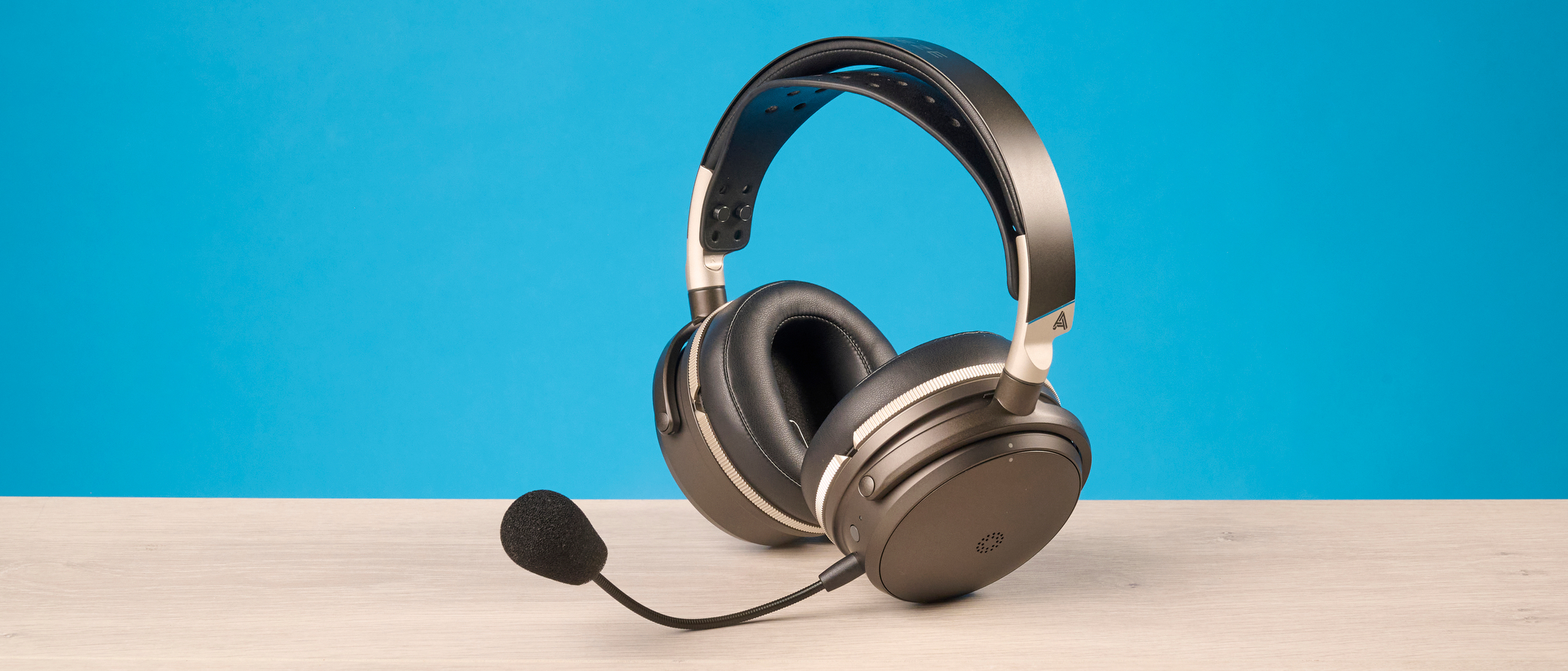 The Audeze Maxwell 2 ANC on a wooden desk with a blue background