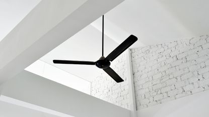 A black ceiling fan on a white brick pitched roof