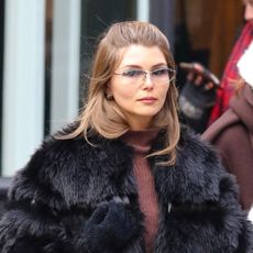 Olivia Jade wearing a black fur coat, brown turtleneck, jeans, a structured frame bag, and black block-heel ankle boots