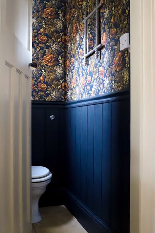 Small bathroom with dark panelled walls and floral wallpaper