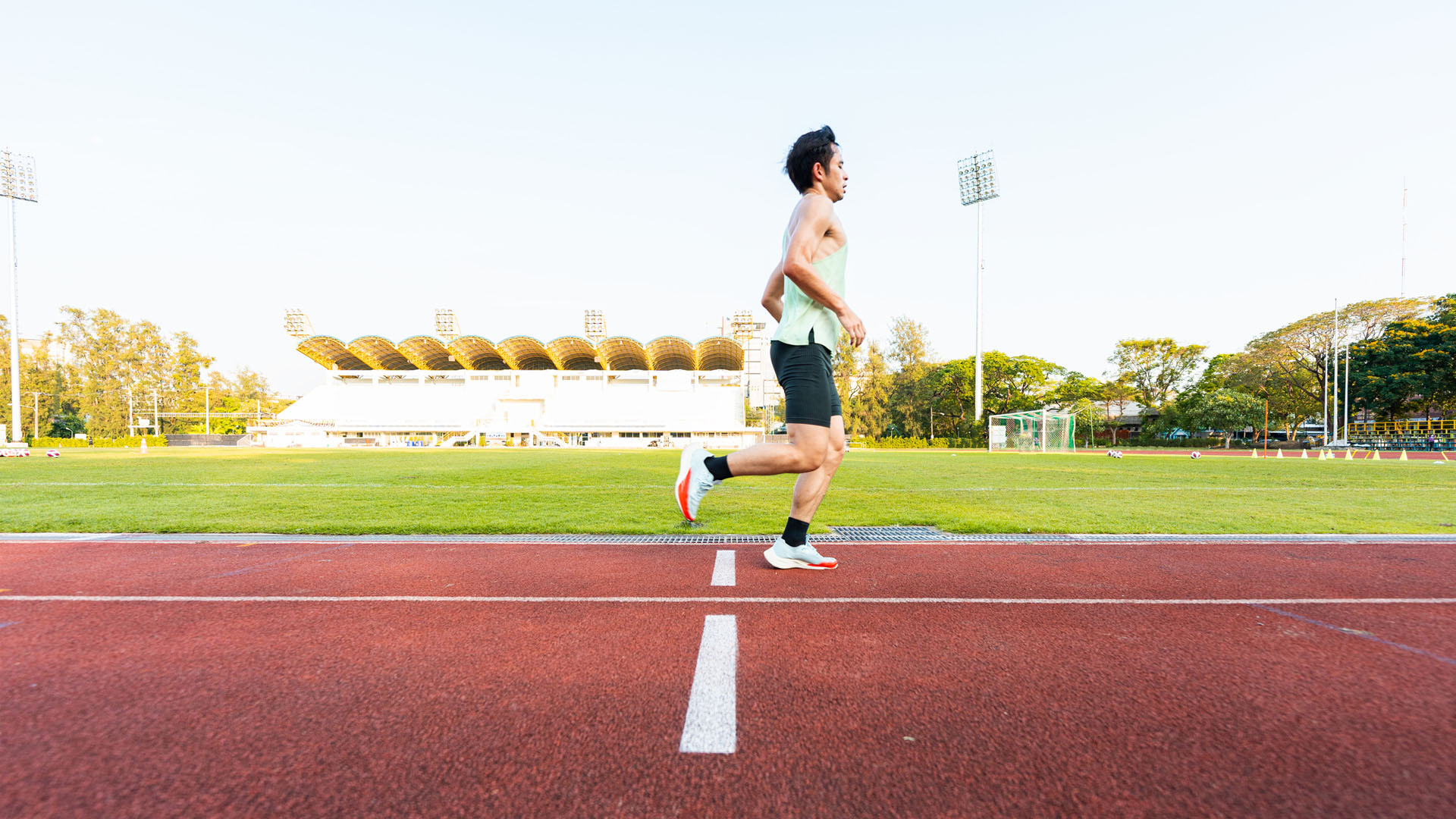 Asian man running on an athletics track