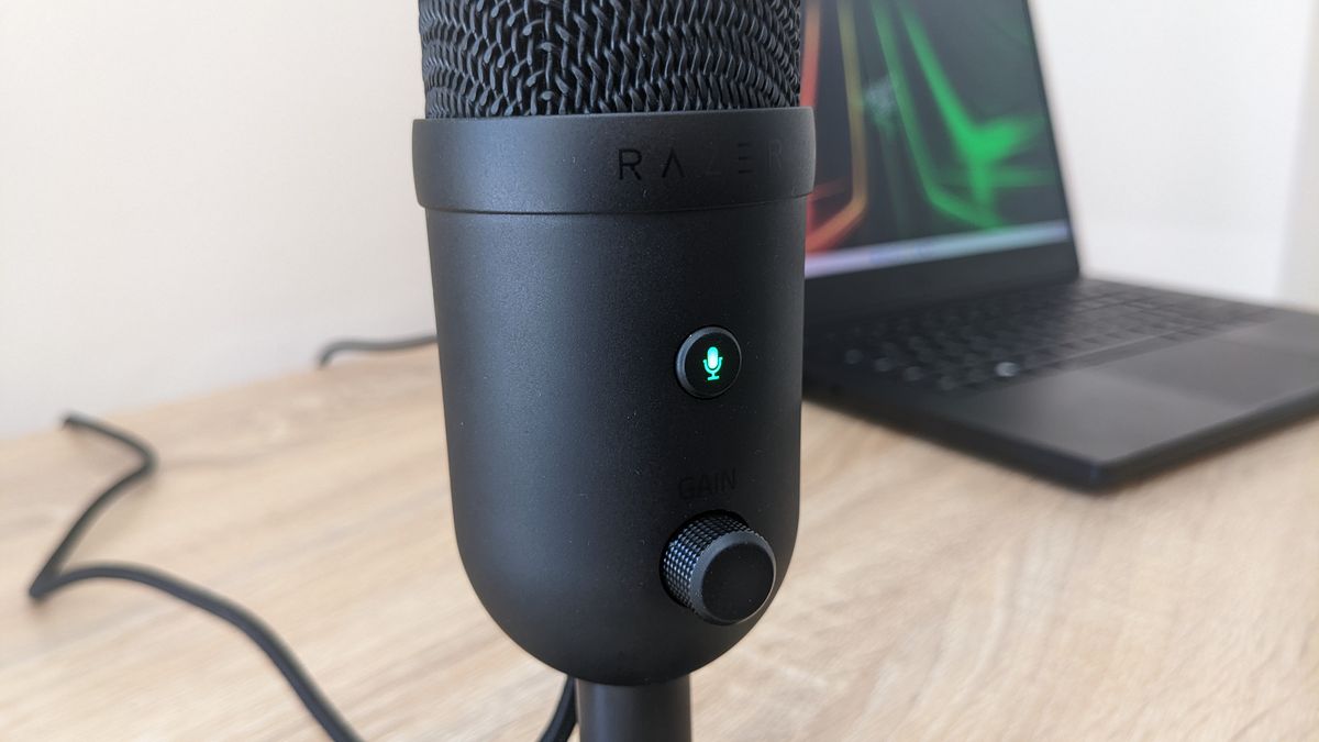 Razer Seiren V2 X USB microphone on a wooden desk, plugged into a Razer Blade 14 laptop.