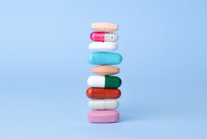 Assorted pharmaceutical drugs balancing on each other, conceptional idea . Blue background.