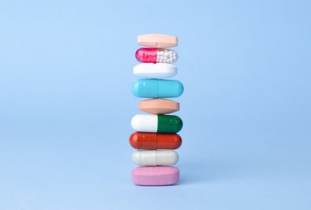 Assorted pharmaceutical drugs balancing on each other, conceptional idea . Blue background.
