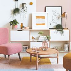 A living room with a pink chair and colour-blocked rug