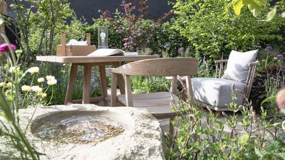 A wooden dining set at the center of a show garden at the RHS Chelsea Flower Show 2026