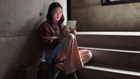 A lady sitting on some concrete steps holding an iPad