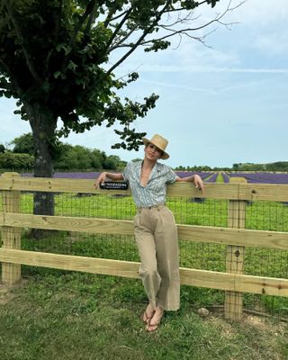 Jennifer Lopez is wearing cropped pants, flip flops, a blouse and a straw hat.