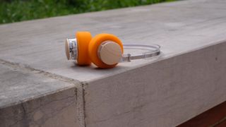 A photograph of the FiiO EH11 over-ear headphones with a transparent frame and orange foam earpads.