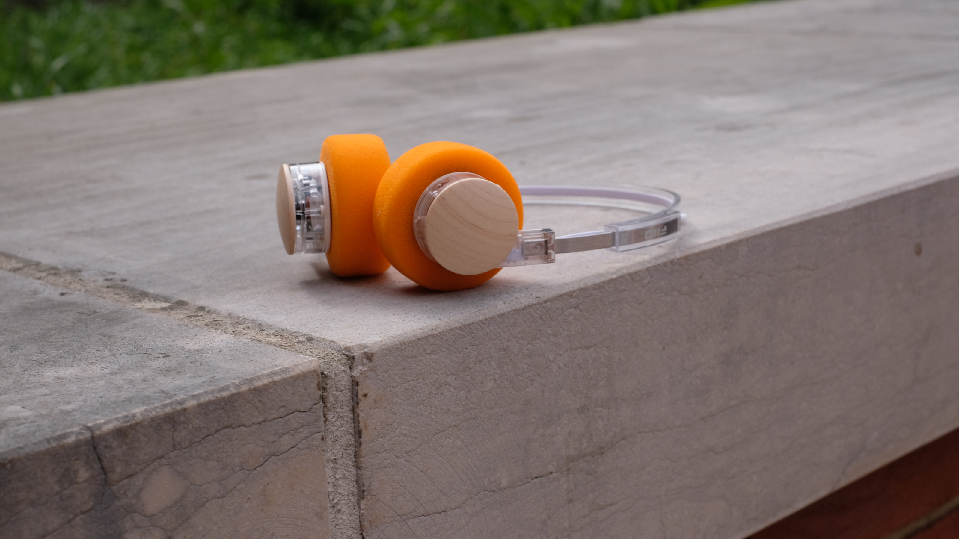 A photograph of the FiiO EH11 over-ear headphones with a transparent frame and orange foam earpads.
