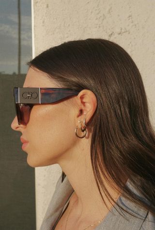 a close photo of a woman wearing sunglasses with a stacked double pierced hoop earrings