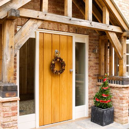 house exterior with brick wall yellow door wreath and plant