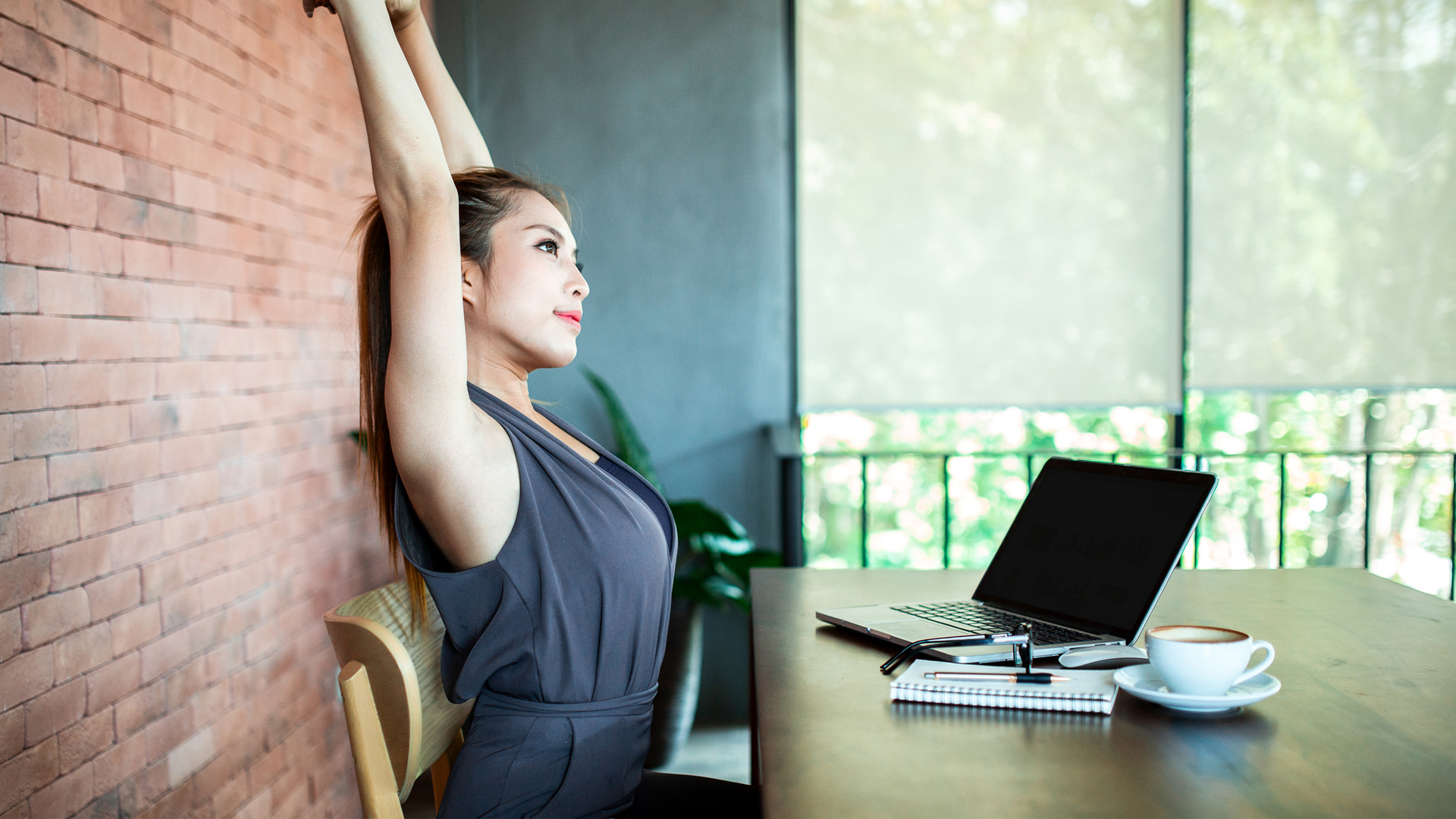 Qué es el ejercicio debajo del escritorio: la imagen muestra a una mujer estirándose en un escritorio