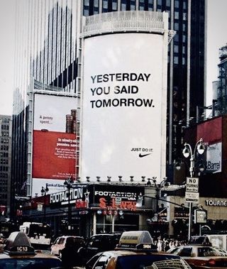 A large white Nike billboard featuring the phrase "yesterday you said tomorrow" in larger black font