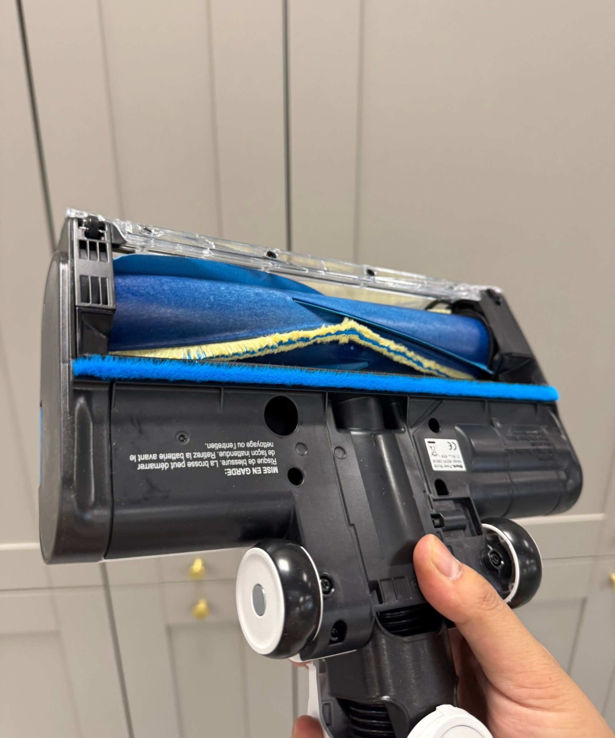 Closeup of the Shark PowerPro Pet cordless vacuum&#039;s floorhead, revealing blue and yellow fins and a black underside.