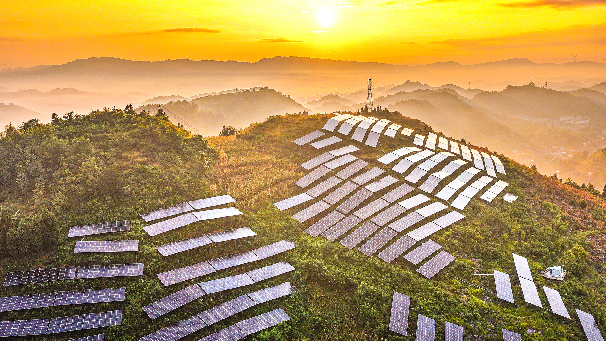 Sun rises over solar panels arranged on a hillside at an agricultural photovoltaic power station in Qianxi City, China