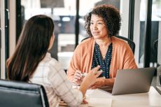 Two women discussing financial advice at an office desk