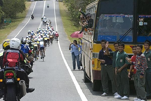 The peloton pass a local school bus in the closing kilometres of stage three.