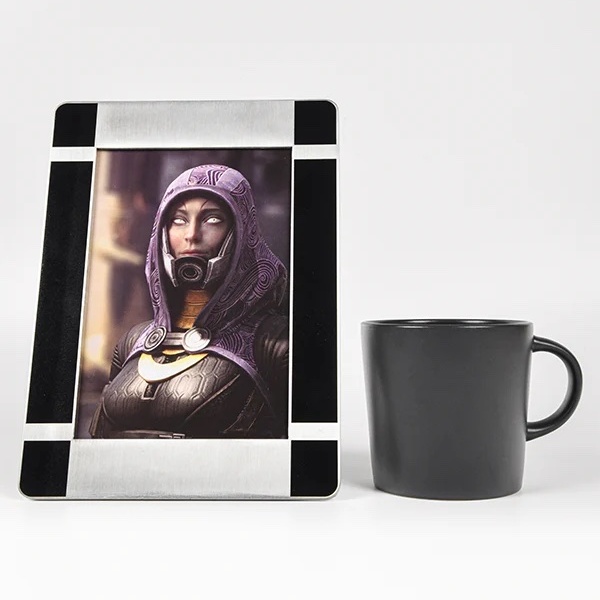 A framed portrait of Tali from Mass Effect, without her mask, next to a coffee cup.