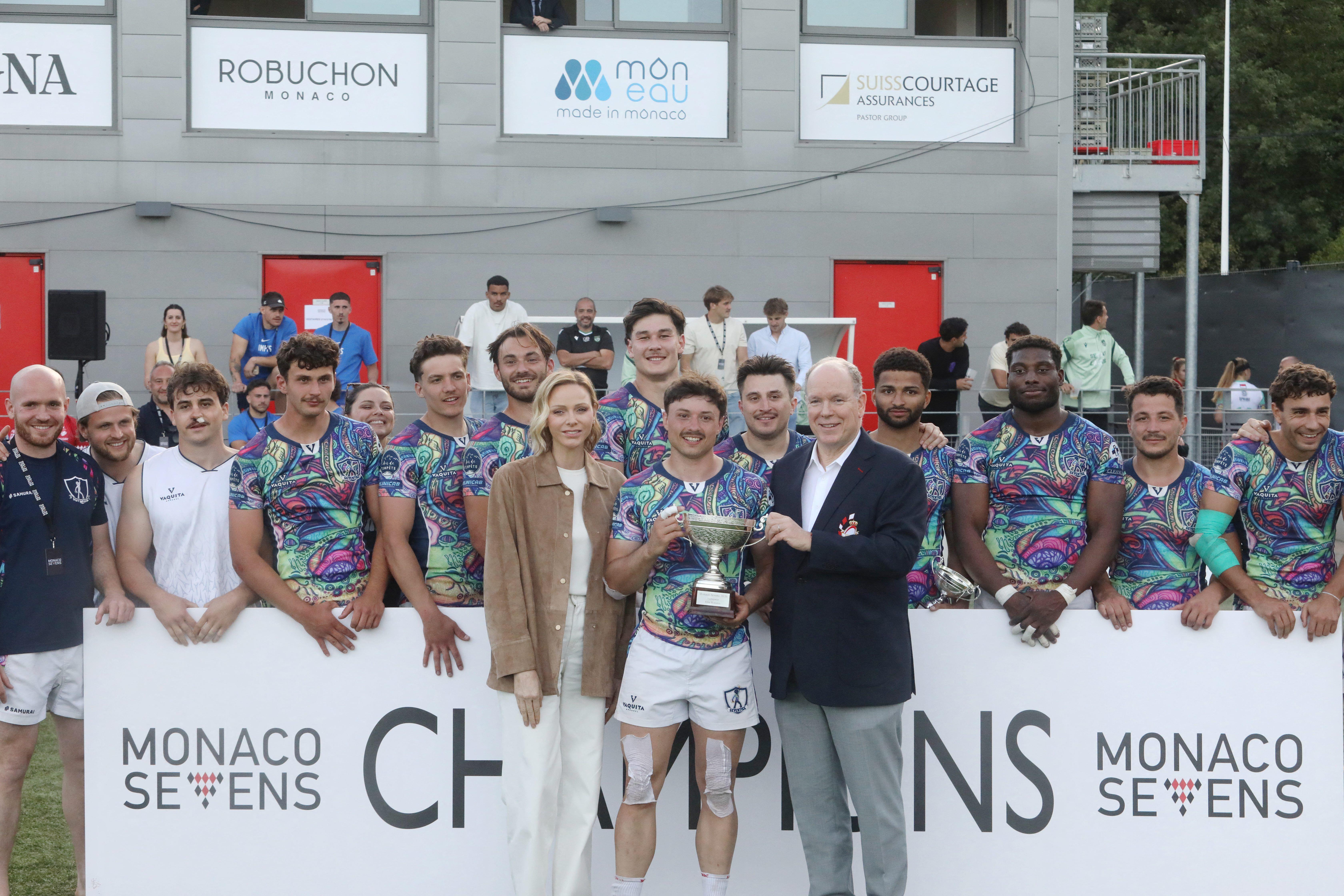 Princess Charlene and Prince Albert presenting a trophy to a rugby player
