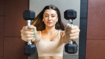 Girl exercising with dumbbells lying on the floor