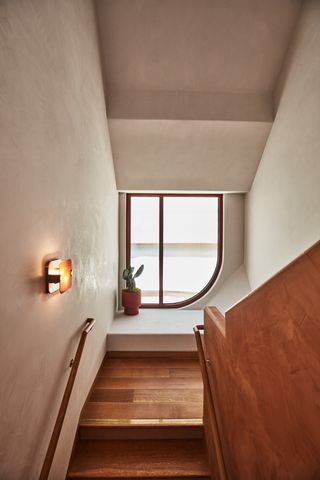 A hallway in the hotel with wooden floors and steps, a wooden handrail and an asymmetric window