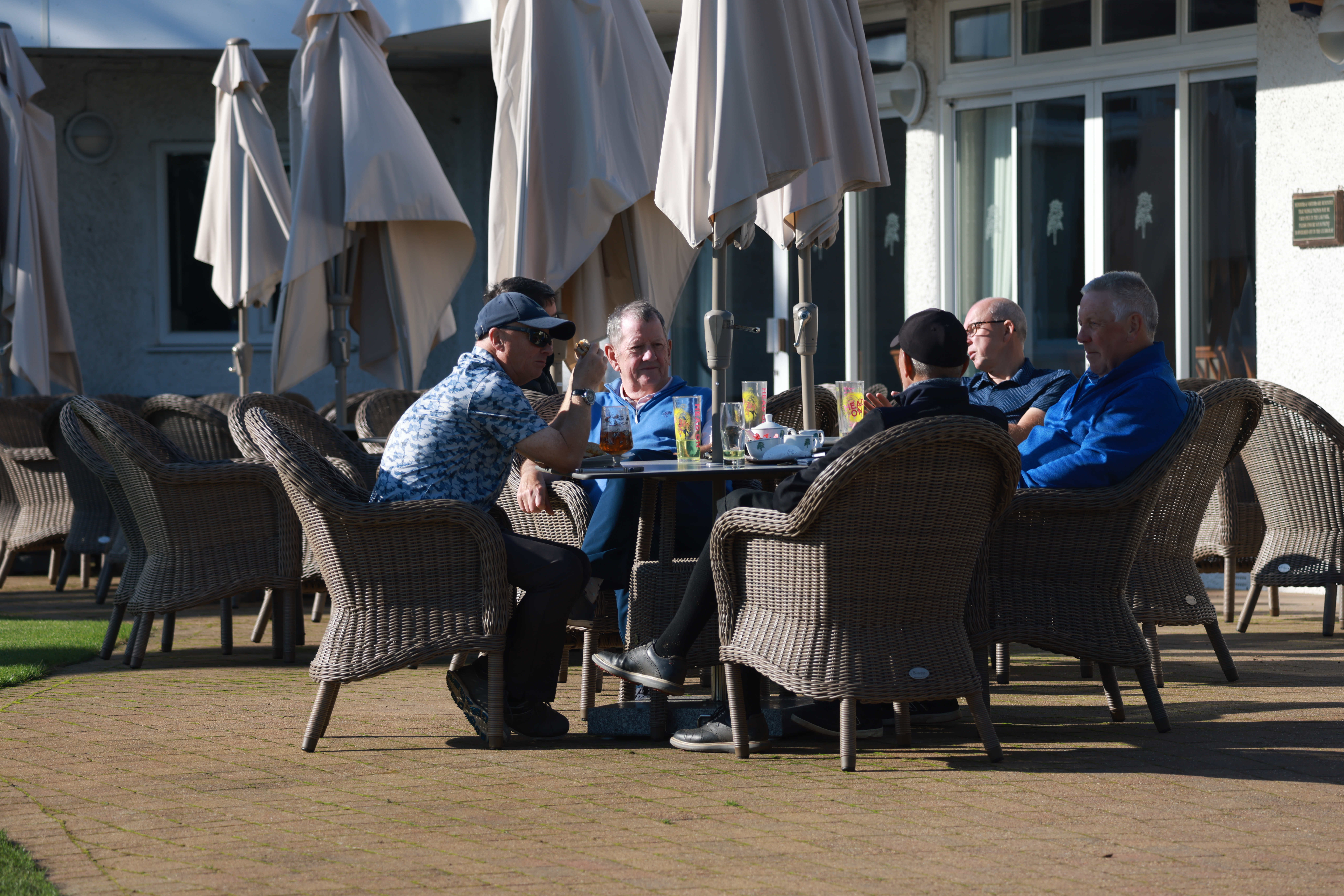 Golfers sit on a table chatting with drinks