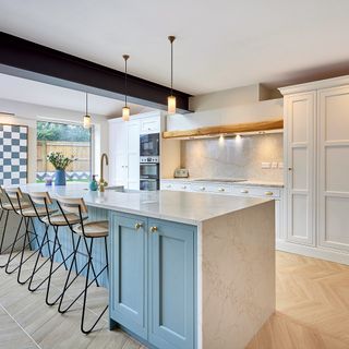 Blue kitchen in a light room with wood flooring