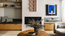 A living room with wall seating, shelving, a coffee table and textured decor