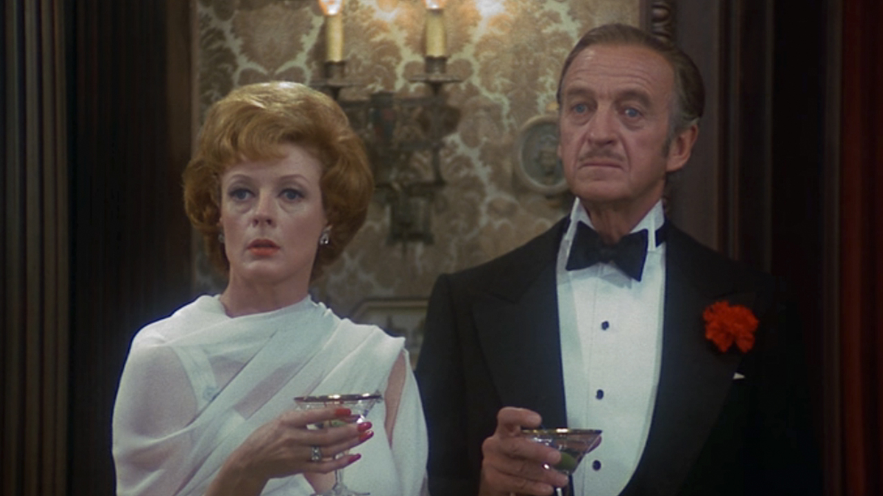Maggie Smith standing next to David Niven, both drinking martinis in formal wear in Murder By Death
