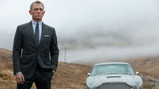 Daniel Craig står iklädd kostym framför sin klassiska bil i Skyfall-filmen.