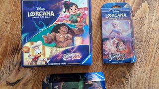 Disney Lorcana Shimmering Skies Illumineer&#039;s Trove and starter sets on a wooden surface