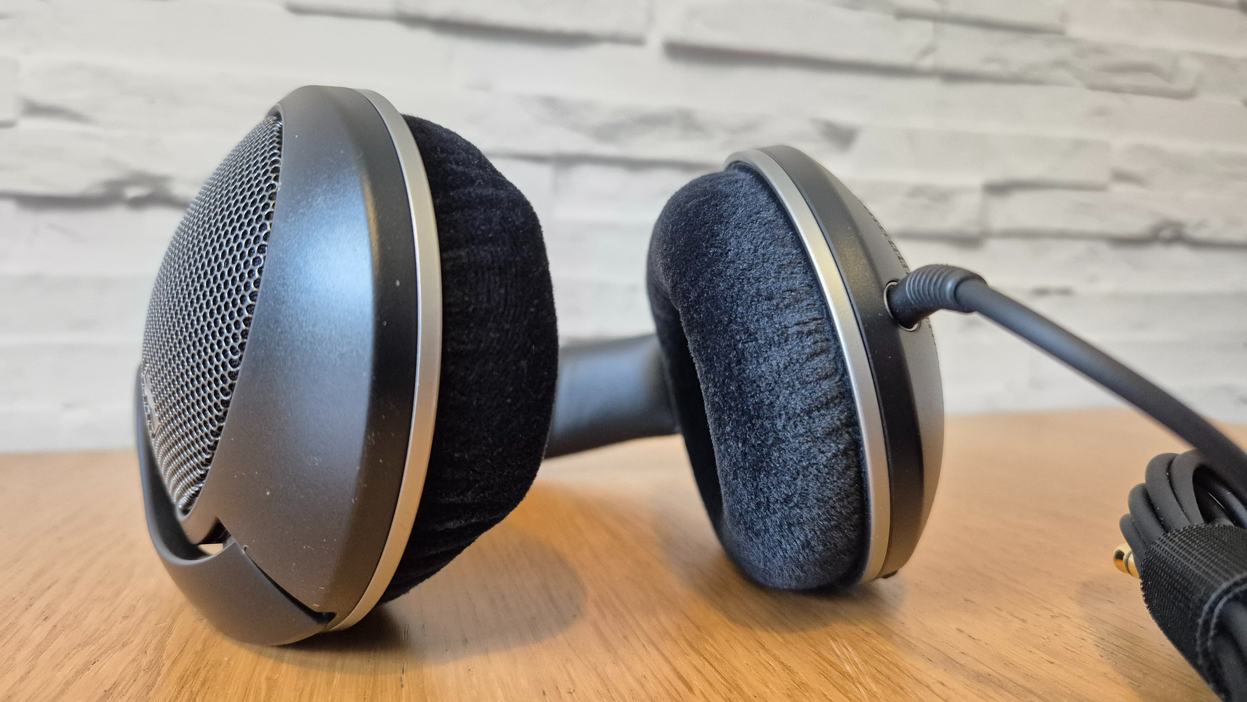 The Sennheiser HD 550 headphones on a wooden surface in front of a white brick background