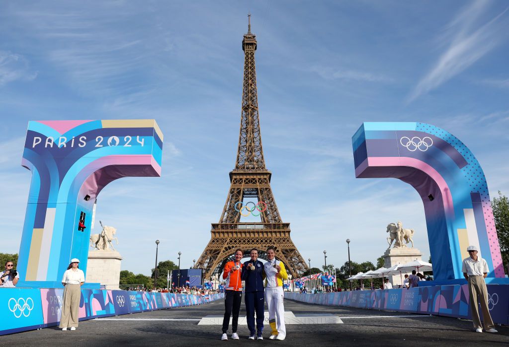 PARIS FRANCE AUGUST 04 Gold medalist Kristen Faulkner of Team United States C Silver medalist Marianne Vos of Team Netherlands L and Bronze medalist Lotte Kopecky of Team Belgium R pose on the podium with the Eiffel Tower in the background during the Womens Road Race on day nine of the Olympic Games Paris 2024 at Trocadero on August 04 2024 in Paris France Photo by Alex BroadwayGetty Images