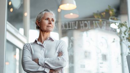 Mature businesswoman standing with arms crossed in cafe