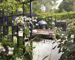 A contemporary urban garden screened with black open panels around a decked seating area